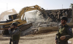 A Caterpillar bulldozer razes a Palestinian building in the West Bank.