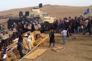 A line of police move towards a roadblock and encampment of Native American and environmental protesters near an oil pipeline construction site, near the town of Cannon Ball